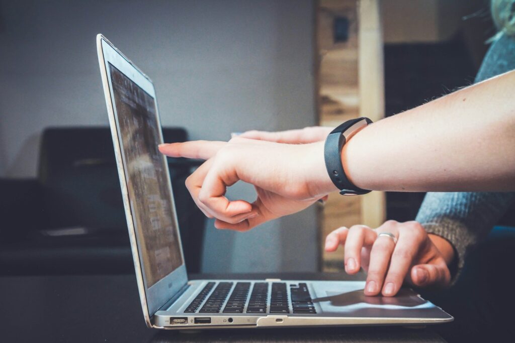 person using laptop with another person pointing at the screen