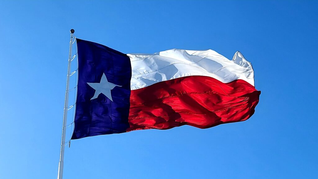 blue white and red Texas flag against a blue sky