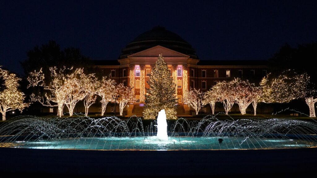 a lighted christmas tree in front of a building