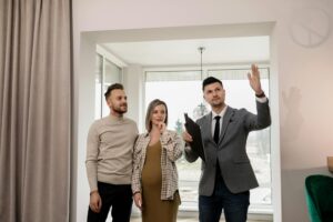 a man and a woman being shown a house by a male real estate agent in a suit