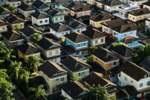 aerial photo of a neighborhood with palm trees, colorful houses and dark roofs