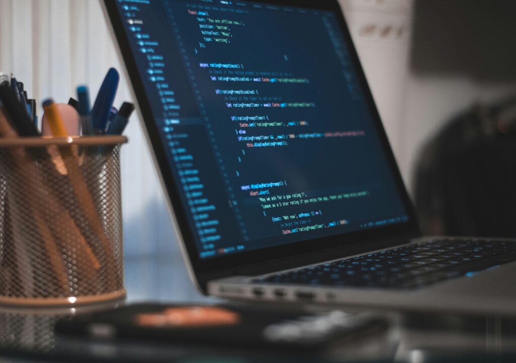 Code on a Macbook screen sitting on a desk next to a pencil cup