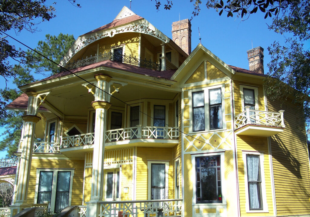 Yellow Victorian home shaded by trees