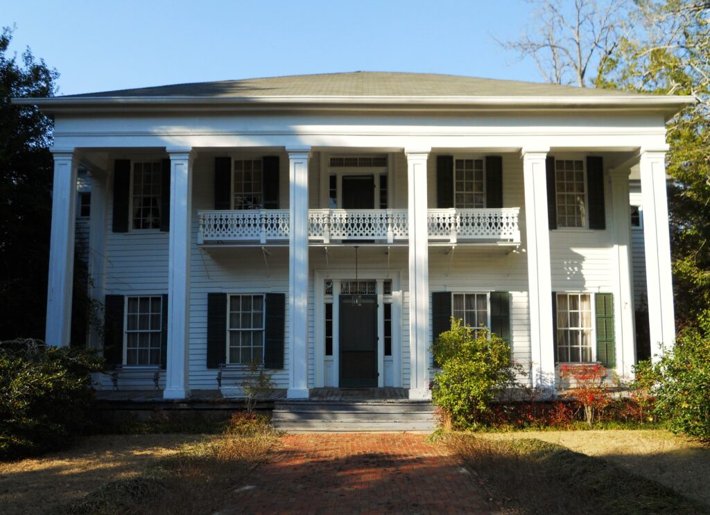 A historic Greek revival home with six white columns and an upper balcony