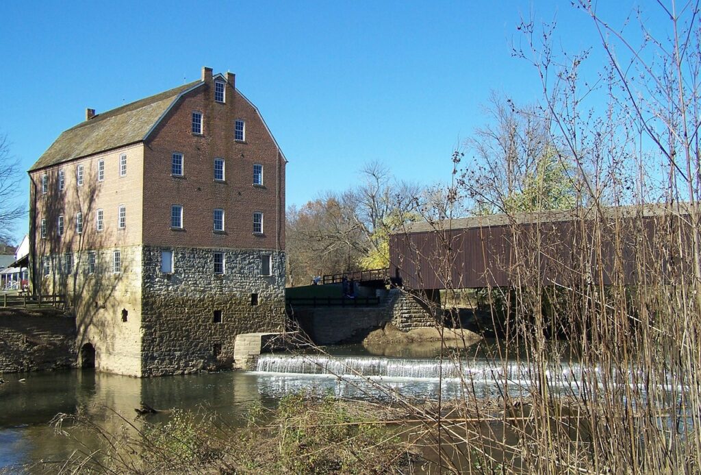 A grist mill against a blue sky in Missouri with trees bare of leaves